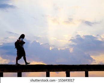 silhouette of woman walking on the pathway, on sunset sky background