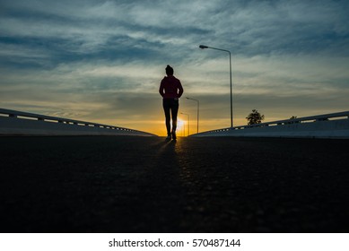 Silhouette Woman Walking On The Street At Sunset.