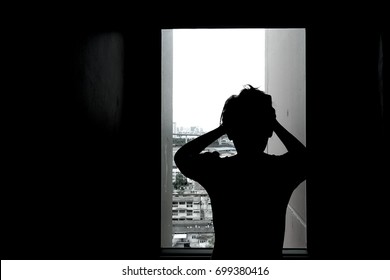Silhouette of woman in window of a room. Sad emotions, crazy, disappointed. Light and darkness