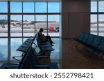 Silhouette of woman working on laptop and waiting for flight in the Airport-Busy - A woman waiting for her flight, which was delayed, at the airport in snowy weather - Oslo