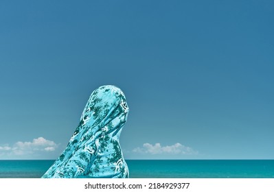 Silhouette Of A Woman Wrapped In A Scarf Against A Gust Of Wind Against The Background Of The Summer Sea And Blue Clear Sky, Weekend At Sea, Cool Breeze