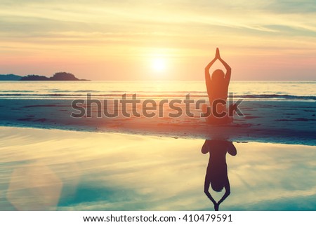 Silhouette woman yoga on the beach at sunset.