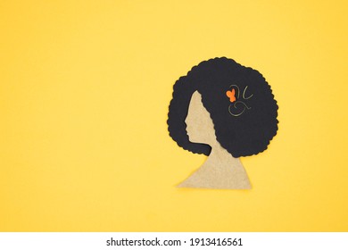 Silhouette Of Woman's Head With Afro Hair Cut In Paper On Yellow Background. Copy Space.