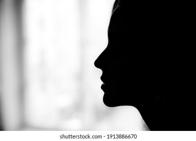 Silhouette of a woman's profile on a background of a window.