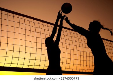 Silhouette women playing beach volleyball on sunset. - Powered by Shutterstock