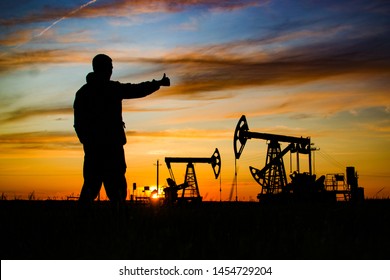 Silhouette of the worker on the background of oil rockers. Sunset. Oil production in Russia. exploration, oil and gas industry