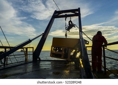 Silhouette of worker recovering robotics Remote Operated Vehicle (ROV) after entering sea surface during oil and gas pipeline inspection in the middle of South China Sea
