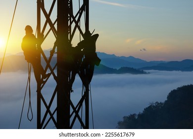 Silhouette workers on background of construction crews to work on high ground heavy industry and safety concept. Construction of the extension of high-voltage towers on beautiful nature background.