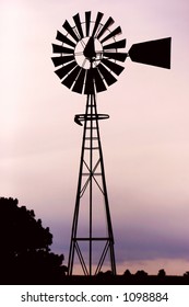 Silhouette of a working vintage country Windmill in sunset light or twilight.