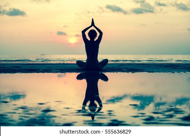 Silhouette Yoga Woman On The Sea Beach At Sunset.