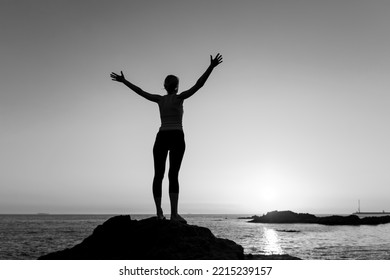 Silhouette Of A Yoga Woman Seeing Off The Sun On The Sea. Black And White Photo.