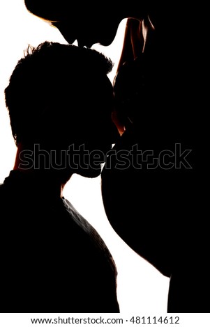 Silhouette of a yong man kissing the belly of his pregnant wife