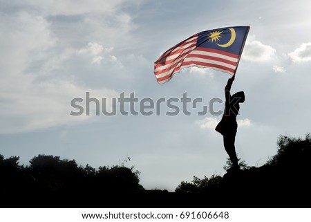 Silhouette of a young asian boy holding the malaysian flag celebrating the Malaysia independence day and Malaysia day