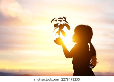 silhouette of Young asian girl holding a young plant for planting, on sunset background for World Environment Day concept. - Powered by Shutterstock