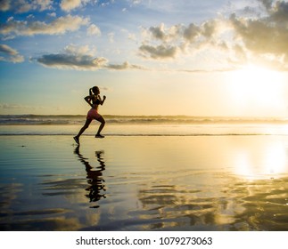 silhouette of young Asian sport runner woman in running workout training at sunset beach with orange sunlight reflection on the sea water in healthy lifestyle and wellness activity concept - Powered by Shutterstock