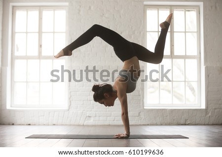 Silhouette of young cool attractive yogi woman practicing yoga concept, standing in Adho Mukha Vrksasana exercise, Downward facing Tree pose, working out, wearing sportswear bra and pants, full length