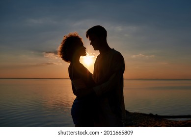 Silhouette of young couple kissing and hugging each other with sunset on background. Romantic date concept