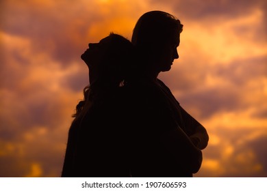 The silhouette of a young couple loving each other on the background of the sunset. A couple in love at sunset with a copy of the text space.