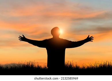 Silhouette of young free man wearing sweater open both arms standing and watched beautiful view sunset alone on top of the mountain. He enjoyed traveling and was successful when he reached the summit.