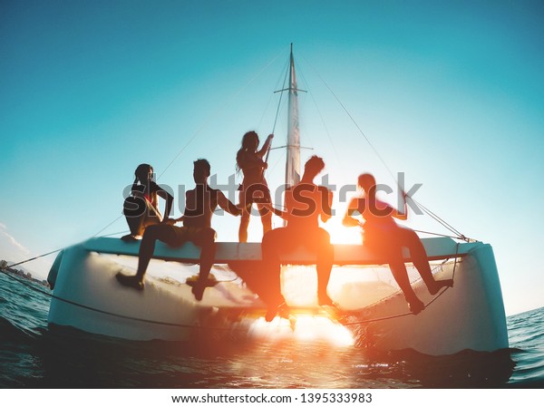 Silhouette of young friends chilling in catamaran\
boat - Group of people making tour ocean trip - Travel, summer,\
friendship, tropical concept - Focus on two left guys - Water on\
camera