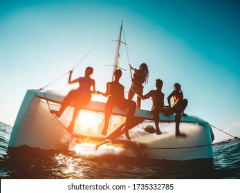 Silhouette of young friends chilling in private catamaran boat - Group of people making tour ocean trip - Alternative travel vacation during Coronavirus outbreak - Focus on left girl - Water on camera