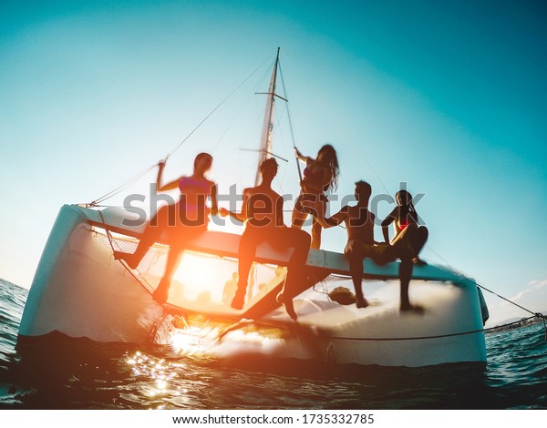 Silhouette of young friends chilling in private\
catamaran boat - Group of people making tour ocean trip -\
Alternative travel vacation during Coronavirus outbreak - Focus on\
left girl - Water on\
camera