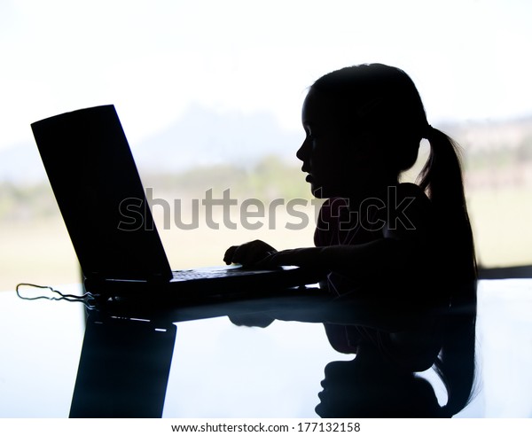 コンピューター上の若い女の子のシルエットが サイバーいじめやインターネットの捕食者によって危険にさらされている可能性があります 彼女は暗がりをしている の写真素材 今すぐ編集