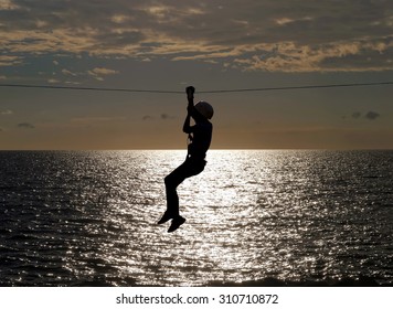 Silhouette Of Young Girl On Zip Line In Summer Sundown 