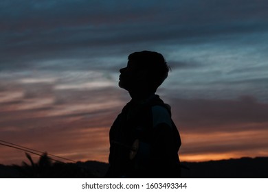 Silhouette Of A Young Indian Boy Looking Up Towards The Sky During The Sunset At Wankaner, Gujarat, India