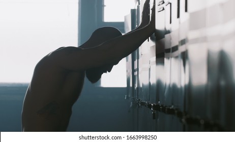 Silhouette of young male athlete alone in dark gym changing room hitting locker, overcoming failure stress and pressure. - Powered by Shutterstock