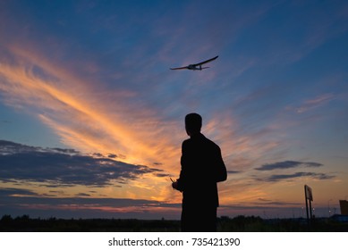 Silhouette of a young man with an airplane rc model at sunset