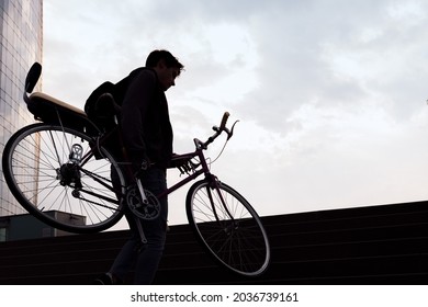silhouette of a young man carrying bicycle up the stairs, concept of sustainable urban transportation and ecological lifestyle, copy space for text - Powered by Shutterstock