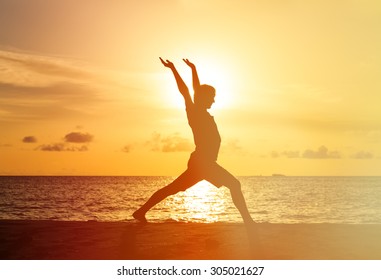 Silhouette of young man doing yoga at sunset beach