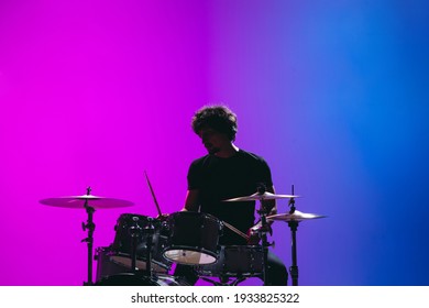 Silhouette Of Young Man Drummer Playing Isolated On Blue-pink Background In Neon