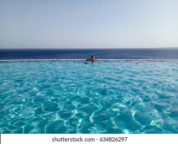 Silhouette of a young man at the edge of infinity swimming pool,looking at the sea.