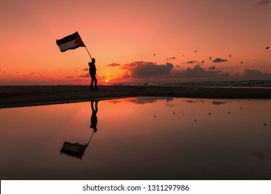 Silhouette Of Young Man Hold A Palestine Flag Near Of Gaza Beach.