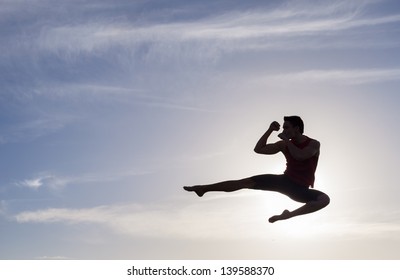 Silhouette of young man jumping, practicing muay thai