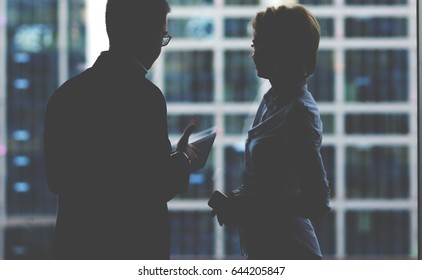 Silhouette of young man managing director holding digital tablet while talking to his woman assistant during work break, successful colleagues using touch pad for discuss ideas after business meeting - Powered by Shutterstock