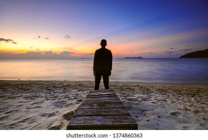 Silhouette of young man on the beach during beautiful sunset.