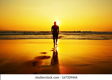 Silhouette of young man on the beach at sunset.  - Powered by Shutterstock