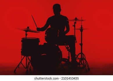 Silhouette of a young man playing drums on a red background.
