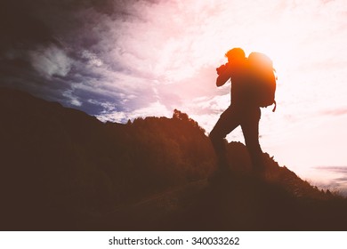 Silhouette of a young man shooting photos in mountain. - Shutterstock ID 340033262