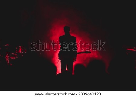 Silhouette of a young man singer during a live music concert with red smoke effect in the background
