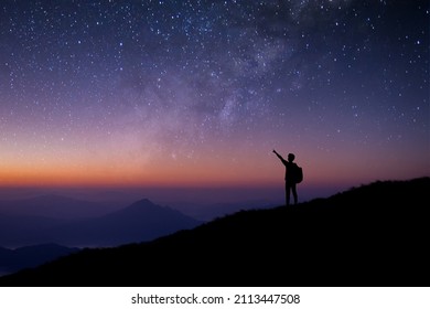 Silhouette of young man standing and open arms watched the star, milky way and night sky alone on top of the mountain. He enjoyed traveling and was successful when he reached the summit. - Powered by Shutterstock