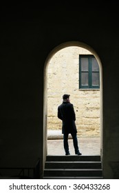 Silhouette Of A Young Man Walking In The City, Shot From Behind