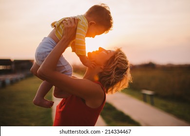 Silhouette Of A Young Mother And Her Little Son At Sunset