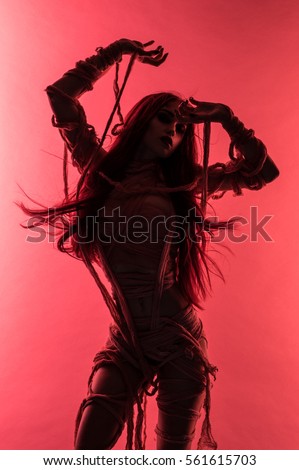 Silhouette of young mummy woman in bandage on pink background