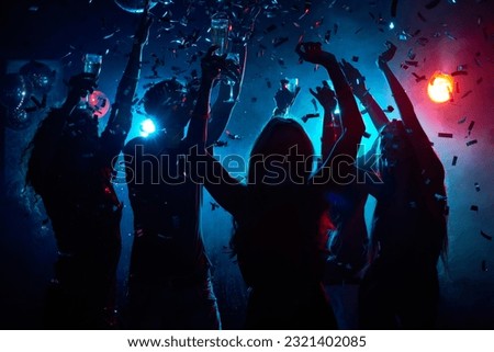 Silhouette of young people with raised flutes having fun and clubbing