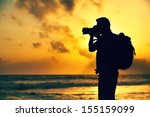 Silhouette of young photographer on the beach