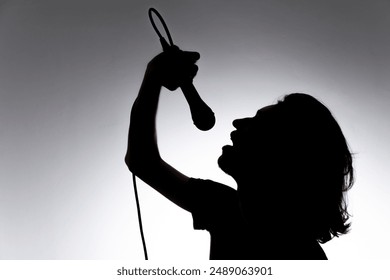 Silhouette of young singer holding wired microphone and singing with emotion. Isolated on white background. - Powered by Shutterstock